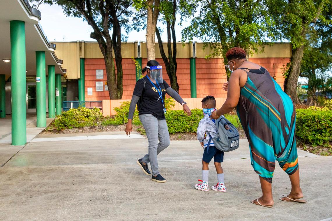 A mother urges her child to go with a teacher at the beginning of the school day at Norwood Elementary School in Miami Gardens, Florida, on Thursday, October 15, 2020.