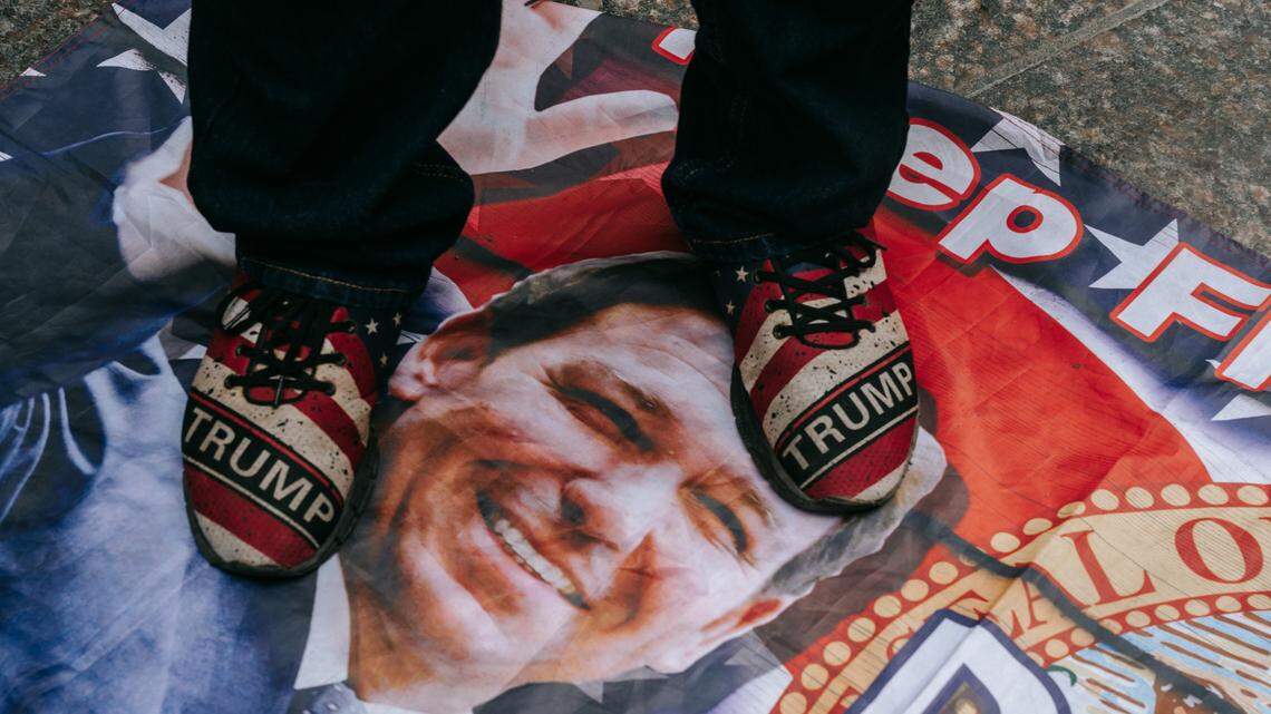 In New York, a man wearing Trump sneakers steps on a flag emblazoned with the face of Florida Gov. Ron DeSantis.