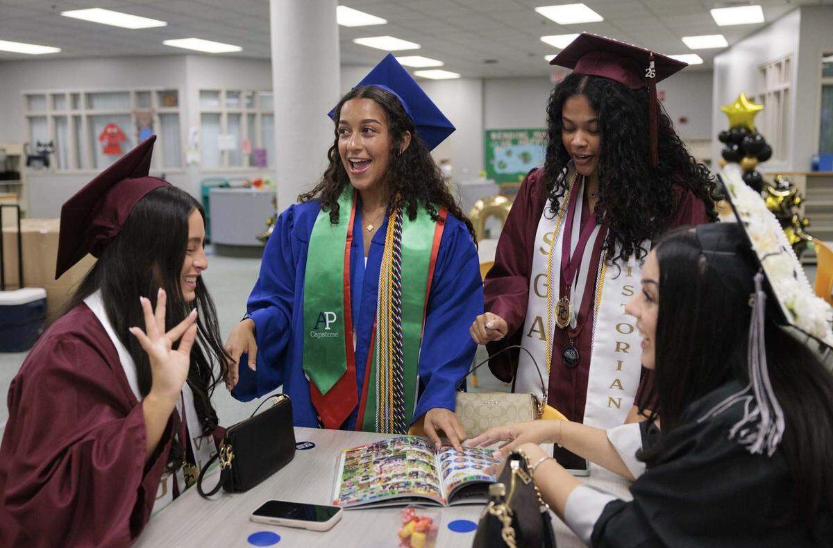 From left to right: Sofia Mejia, Sophia Valdez, Gabriella Gittens, and Sofia Sang, all 18, who now go to different high schools, look at their fourth grade yearbook from Panther Run Elementary before the alumni walk through the halls of their elementary school on Monday, June 1, 2026, in Pembroke Pines, Fla.  The group met in elementary school and remain friends to this day. 