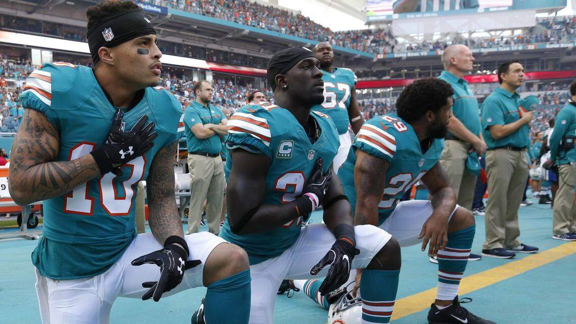 In this Sunday, Oct. 23, 2016, file photo, Miami Dolphins wide receiver Kenny Stills (10), free safety Michael Thomas (31) and defensive back Chris Culliver (29) kneel during the National Anthem before the first half of an NFL football game against the Buffalo Bills.