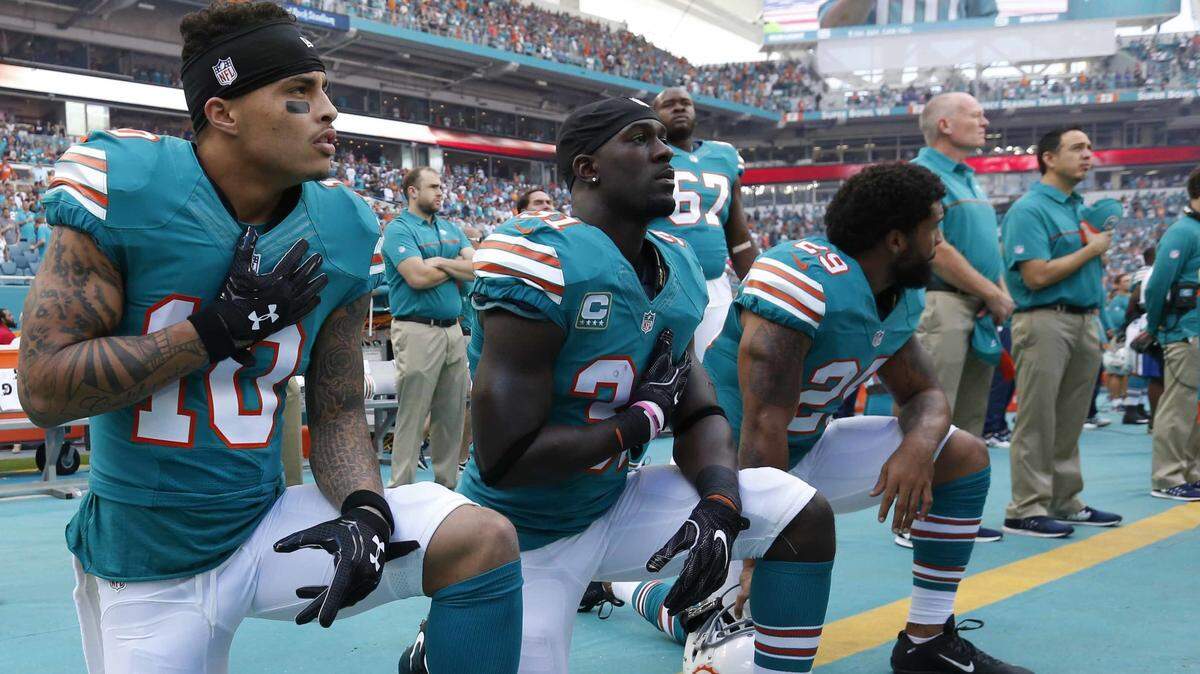 In this Sunday, Oct. 23, 2016, file photo, Miami Dolphins wide receiver Kenny Stills (10), free safety Michael Thomas (31) and defensive back Chris Culliver (29) kneel during the National Anthem before the first half of an NFL football game against the Buffalo Bills.