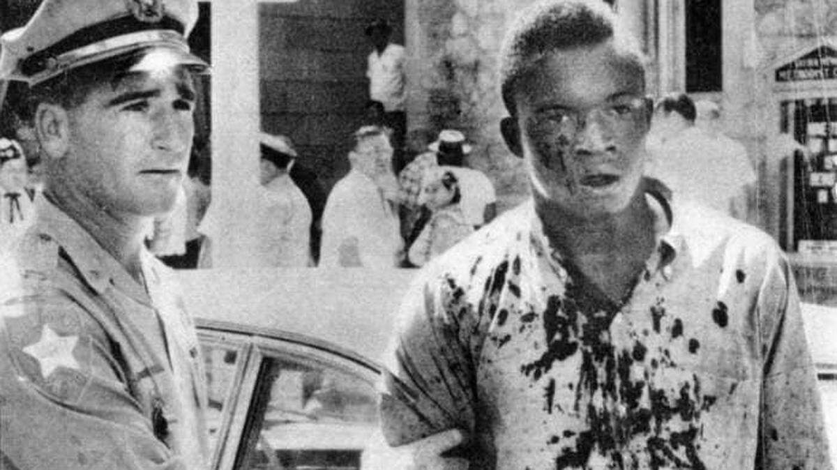 In 1960, a Jacksonville police officer stands with Charles Griffin, who was attacked by members of the Ku Klux Klan wielding ax handles during a lunch counter protest by civil rights activists.
