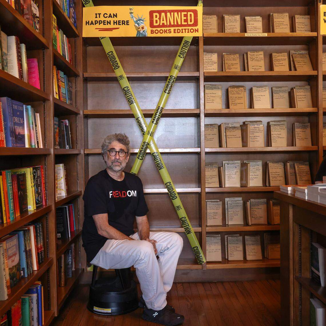 Books and Books owner Mitch Kaplan sits near empty book shelves to illustrate the effects of Florida’s book bans during a “Freadom” event in Coral Gables in 2023.