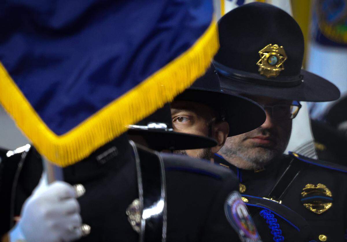 Color Guards representing various agencies line up during a quick rehearsal in preparation of the funeral service for Miami-Dade Deputy Sheriff Devin Jaramillo at Loan Deport Park, where multi-agency officers, public servants, friends, and family members gathered to honor the fallen deputy on Tuesday, November 18, 2025, in Miami, Florida. One guard keeps a close eye and hear as instruction are shared.