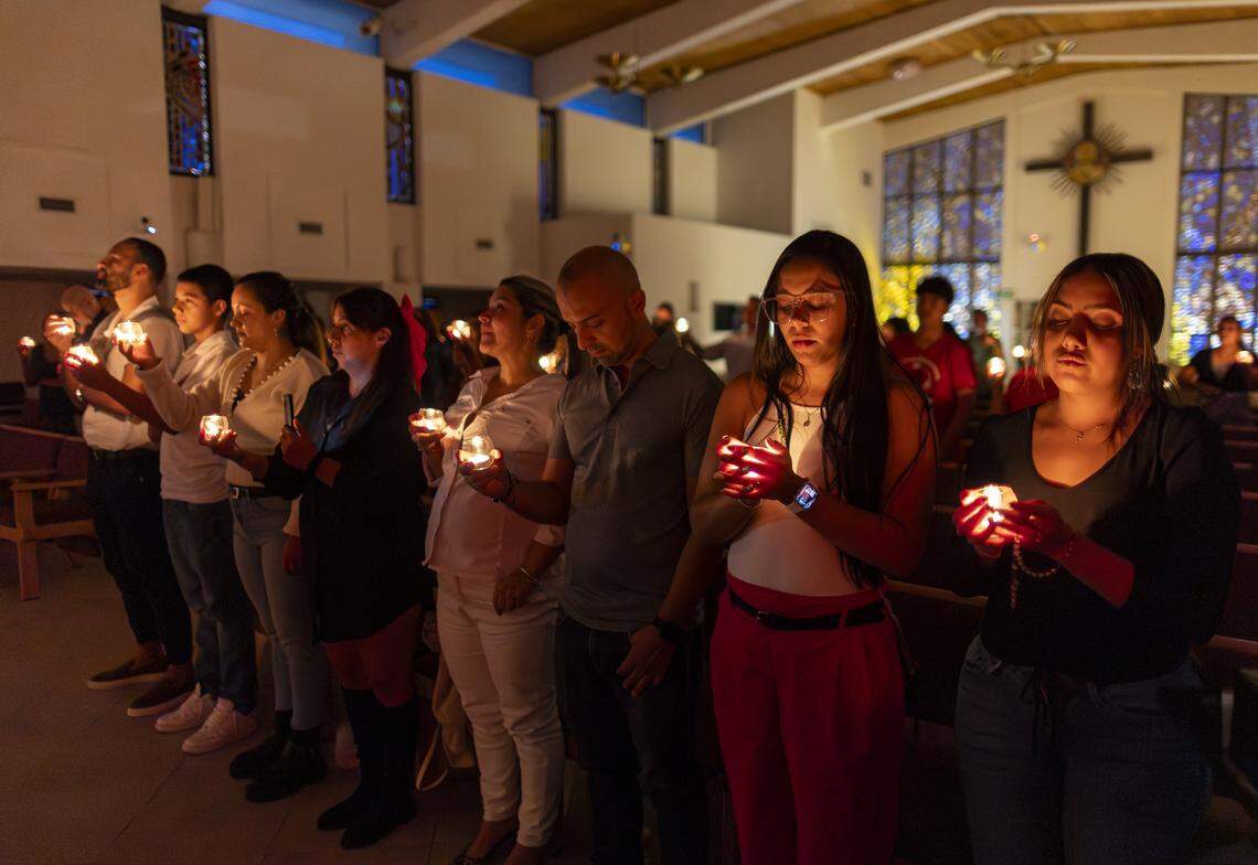 From right to left: Sara Trujillo, Melissa Quiroz, Miguel Pereira, Laura, Yiralit Vanegas, Mayerly Susa, Juan Pablo Susa and Leandro Giraldo hold candles and pray during a vigil at Christ Lutheran Church on Saturday, Aug. 9, 2025, in Oakland Park, Fla. The vigil brought together immigrant families and others supporting loved ones in migrant detention centers, such as Alligator Alcatraz, across the state and country. Laura, who is undocumented, has a 13-year-old son and was recently diagnosed with terminal cancer, watched two months ago as her husband, Luis, was detained by ICE and taken to a detention center in Louisiana.