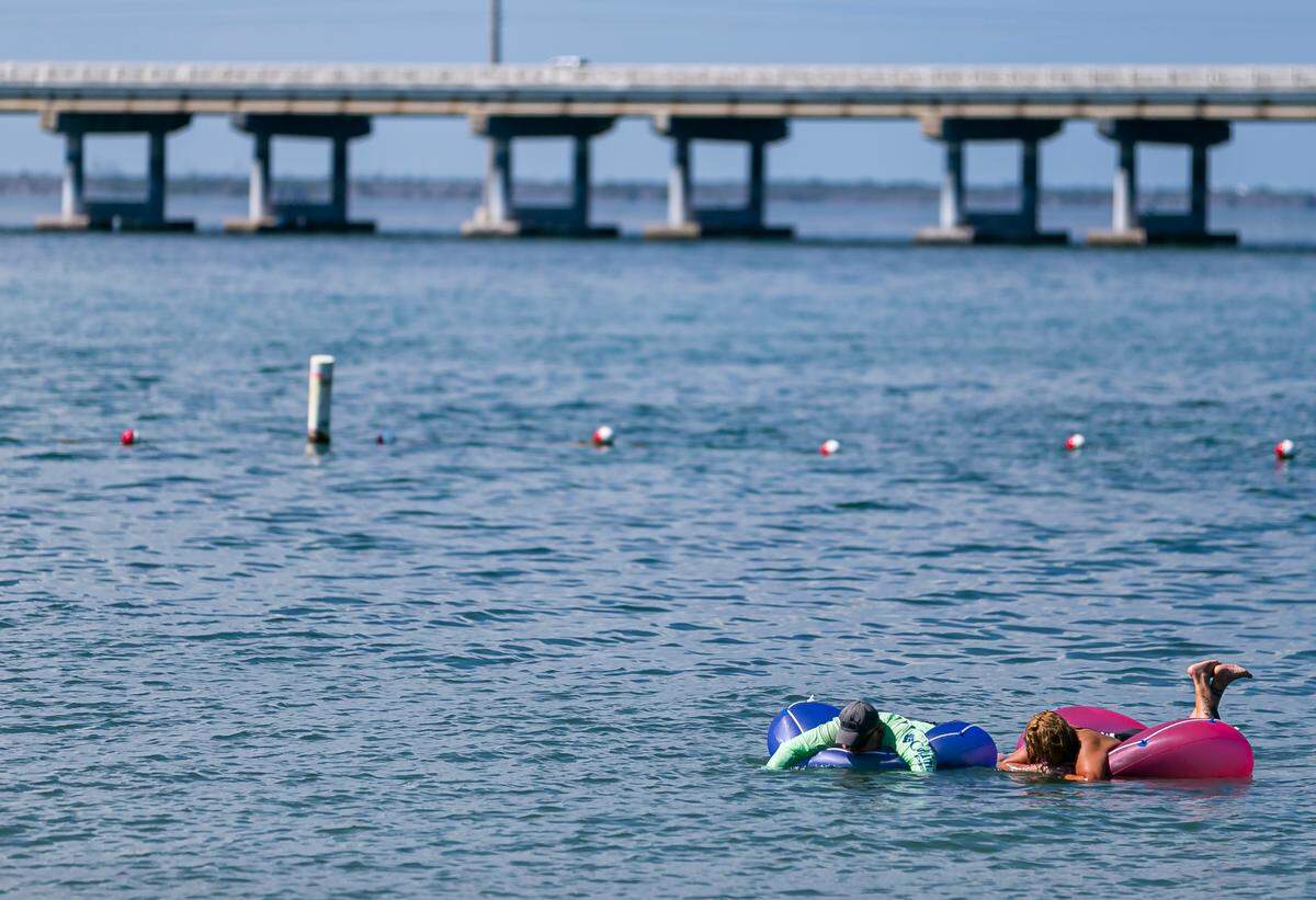 Beachgoers are seen floating on Bahia Honda State Park’s Calusa Beach near Big Pine Key on Monday, October 11, 2021. The Overseas Highway can be seen in the background.