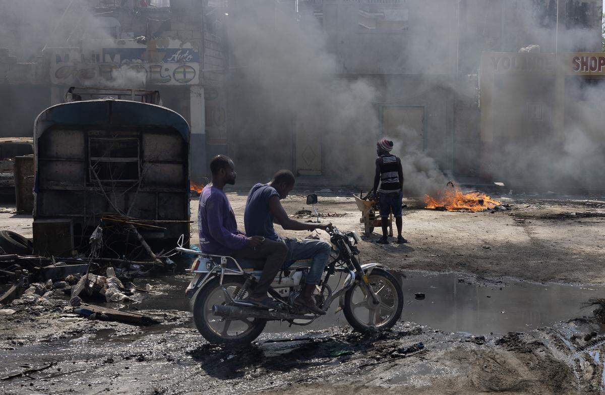A man stands in front of a burned barricade set up by a gang member near the Presidential palace in Port-au-Prince on April 23, 2024.