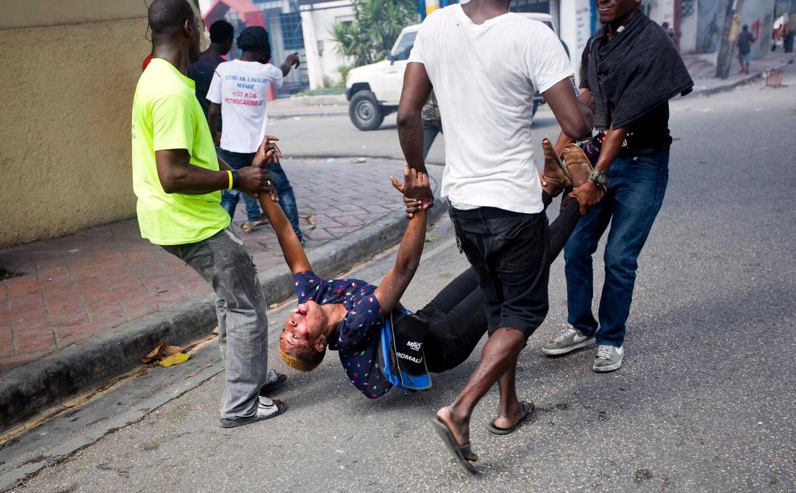 An injured woman is carried away by protesters during clashes with national police officers in Port-au-Prince, Haiti, on Thursday, Feb. 7, 2019. Protesters were calling for the resignation of President Jovenel Moise and demanding to know how Petro Caribe funds have been used by the current and past administrations.