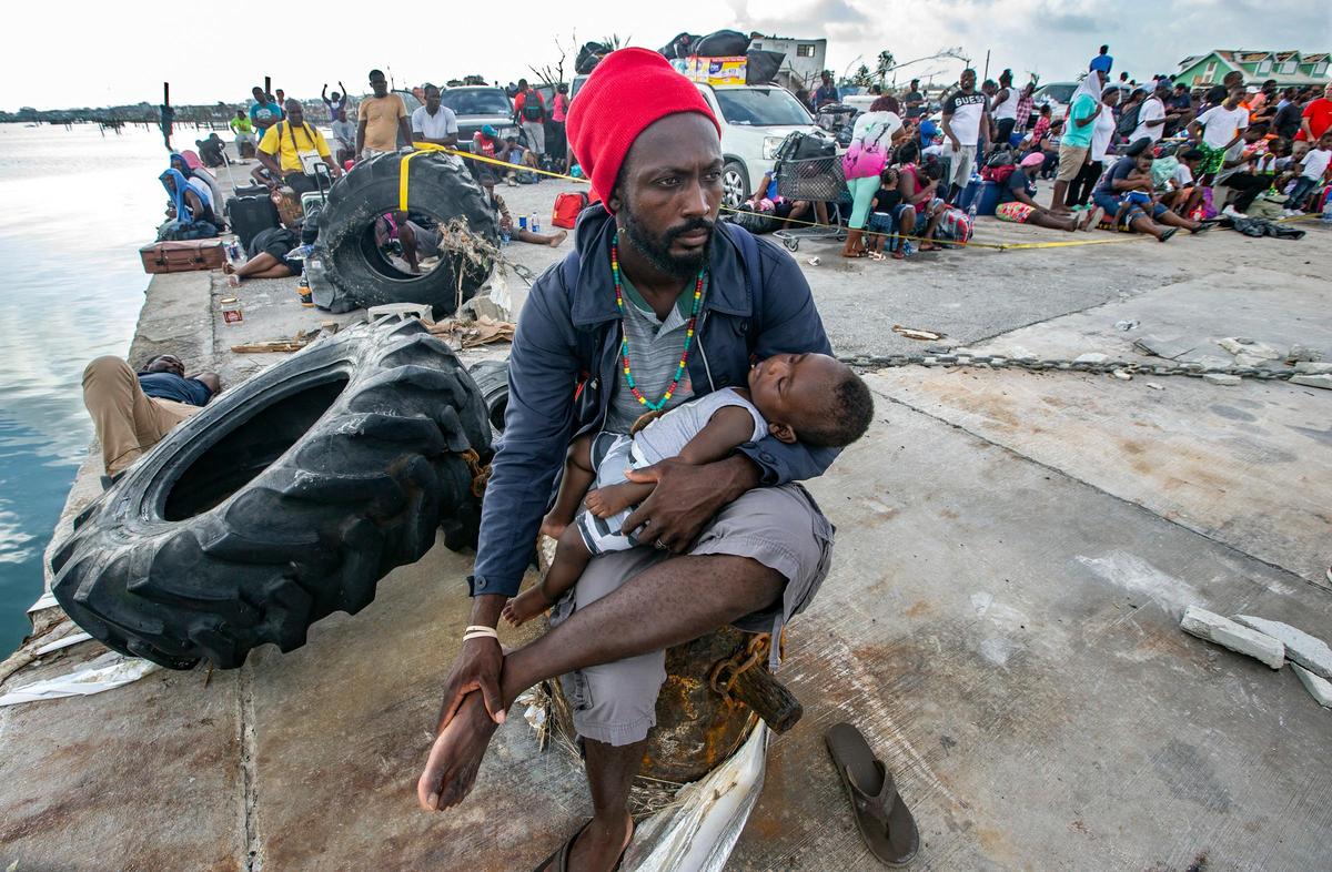 Jean Eugene sostiene a su hijo de seis meses, Linden Eugene, mientras los evacuados se congregan en el puerto de Ábaco este viernes 6 de septiembre de 2019 esperando a salir de la isla.