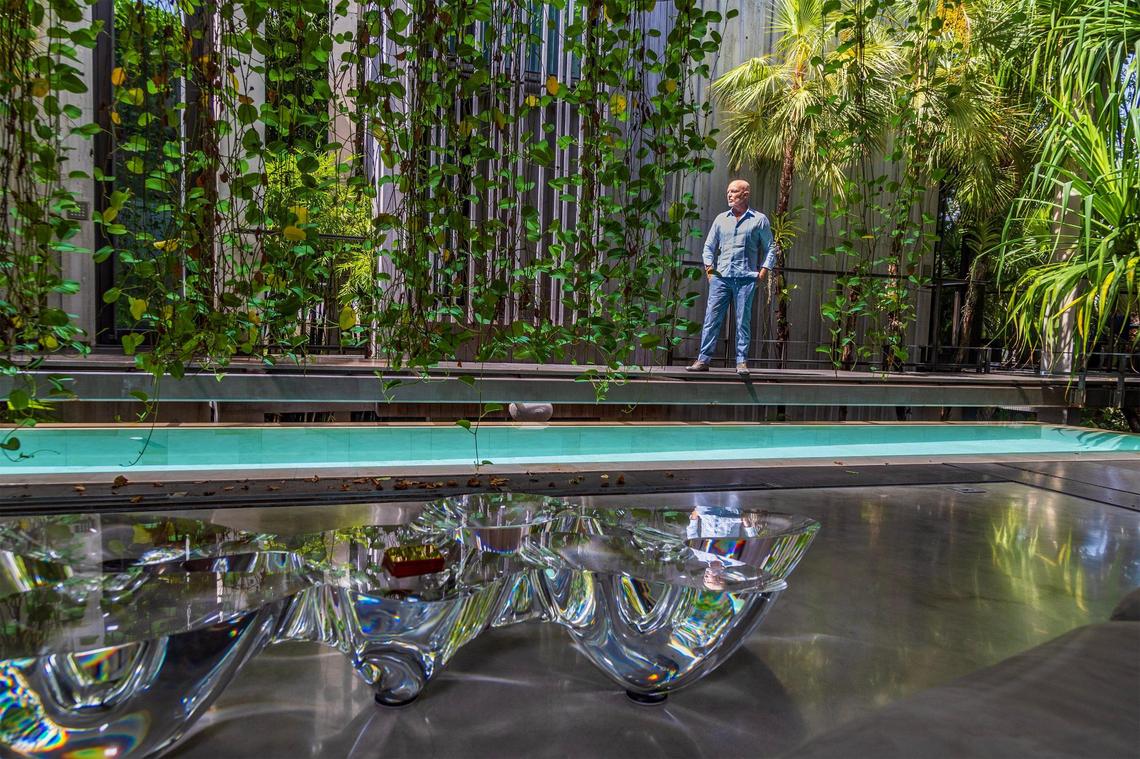 Miami architect René Gonzalez, stands next to a pool that runs through the middle of the Prairie House, a home he designed in Miami Beach.