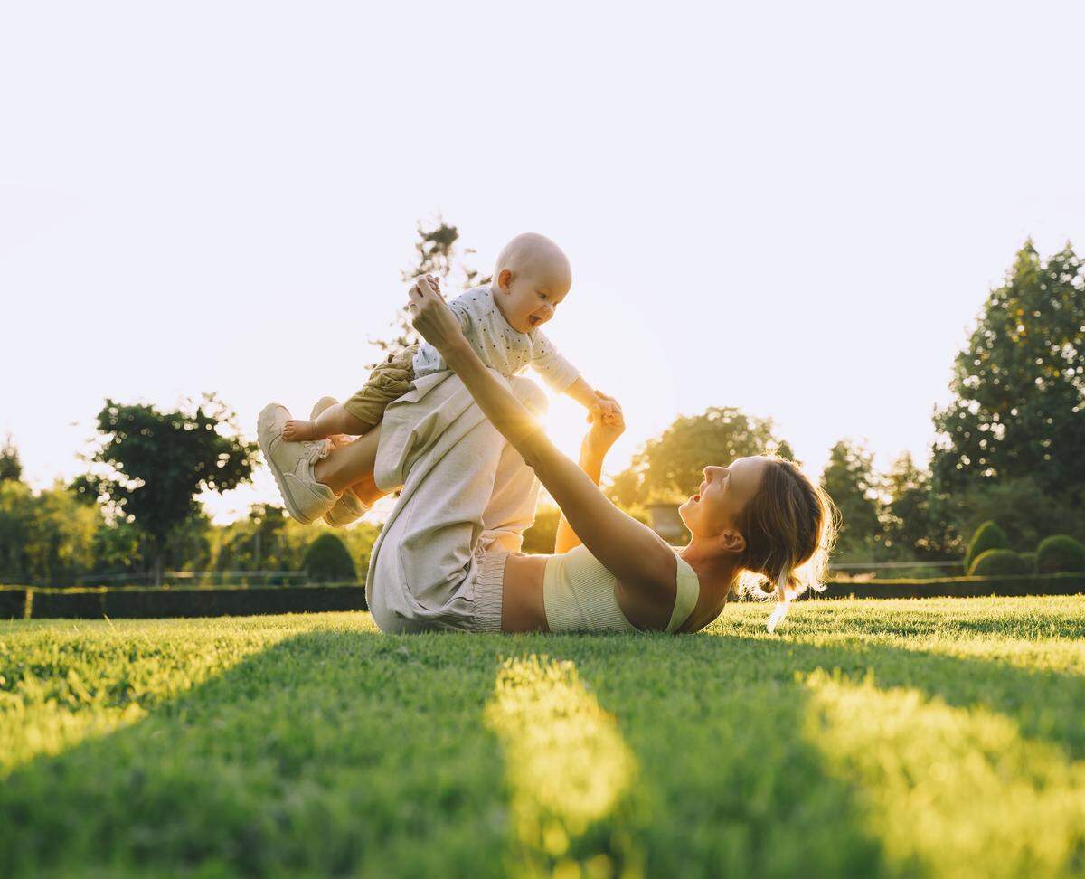 mother daughter playing airplane in grass