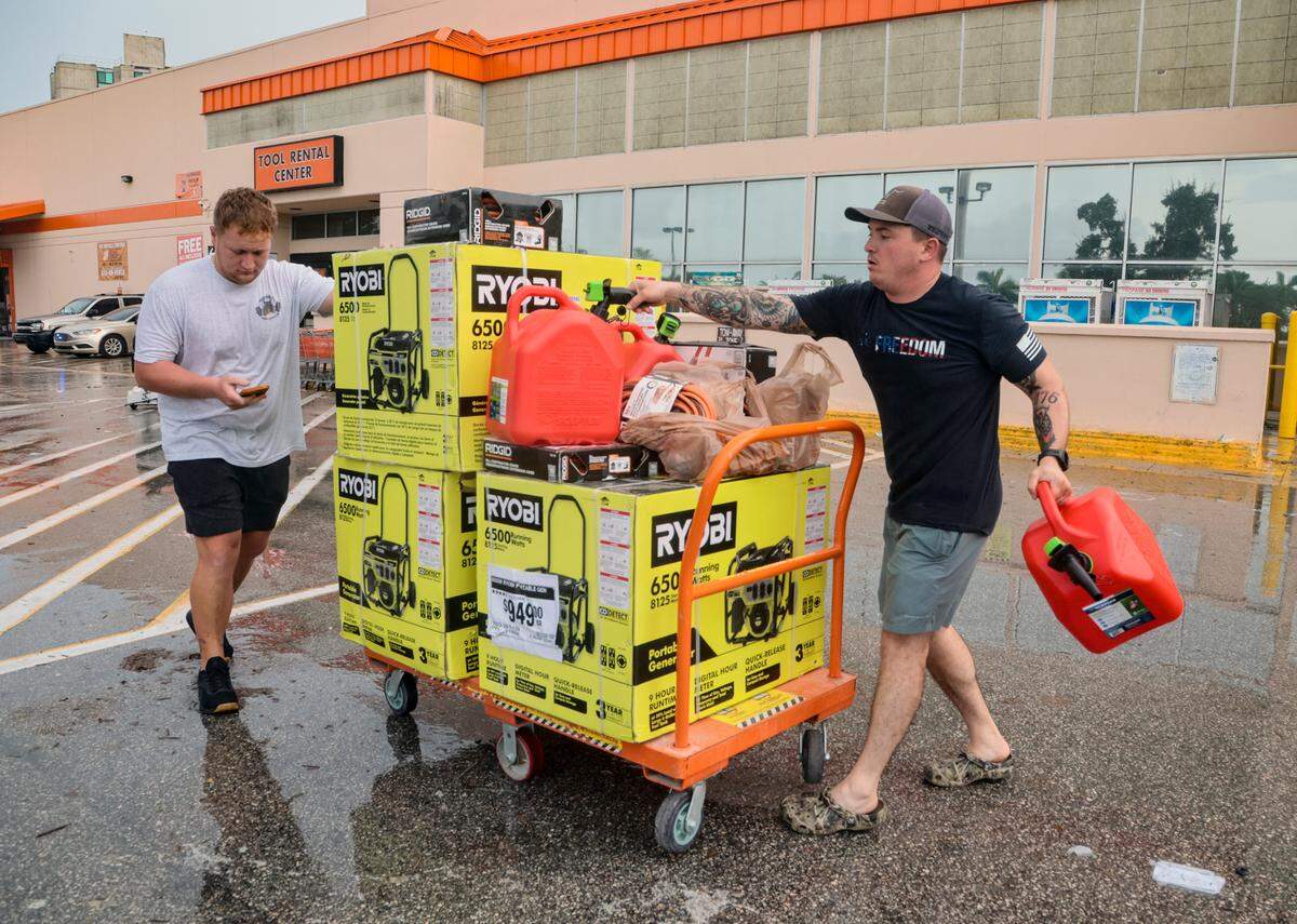 In this file photo from Sept. 28, 2022, Taylor Peat, at left, and Brady Bernstein, at right, of Sarasota, haul a load of generators and supplies for their families back home affected by Hurricane Ian as they leave the Home Depot store on Southwest Eighth Street in Miami’s Little Havana neighborhood.