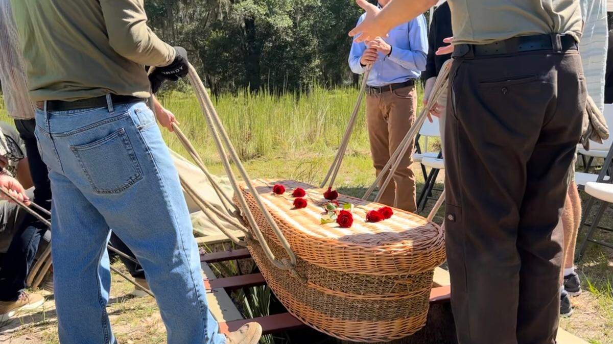 The family of Janet McAliley, a four-term Miami-Dade County Public School Board member, lifts her biodegradable casket into a grave during a funeral service at Prairie Creek Conservation Cemetery.