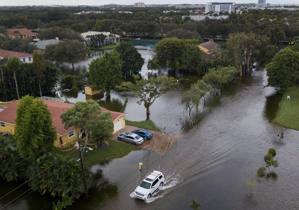A car drives through a flooded street in a residential neighborhood in Plantation, Florida on Monday, November 9, 2020. Tropical Storm Eta made its way past South Florida Sunday night leaving roads and neighborhoods flooded.