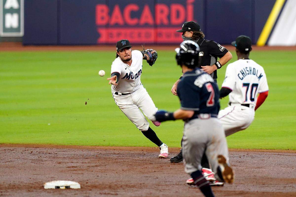 Miami Marlins shortstop Miguel Rojas, left, tosses the ball to second baseman Jazz Chisholm (70) to force out Atlanta Braves’ Dansby Swanson (7) at second for the third out in the second inning in Game 3 of a baseball National League Division Series, Thursday, Oct. 8, 2020, in Houston.