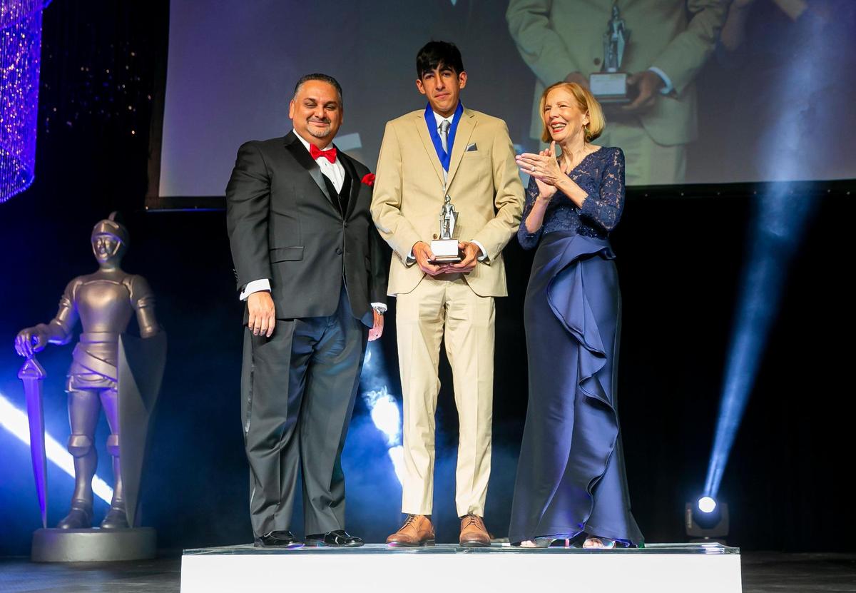 Silver Knight winner in Athletics Carlos Morales, from Belen Jesuit Preparatory School, on stage with his award from Alex Mena, the managing editor of the Miami Herald and el Nuevo Herald, and Joan Chrissos, the education and health editor of the Miami Herald, during the Miami Herald & el Nuevo Herald 64th Annual Silver Knight Awards at the James L. Knight Center in downtown Miami, Florida on Thursday, May 26, 2022.