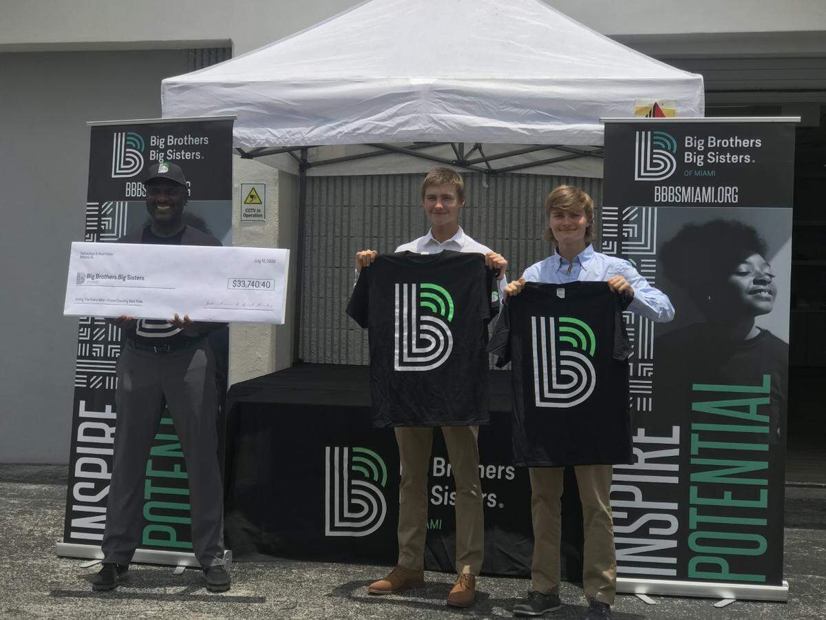 Gale S. Nelson, president and CEO of Big Brothers Big Sisters of Miami, received a check from brothers Sebastian and Axel Hicks, who biked across the country with their dad, Jeffrey Hicks, to raise $33,740 for their favorite organization.