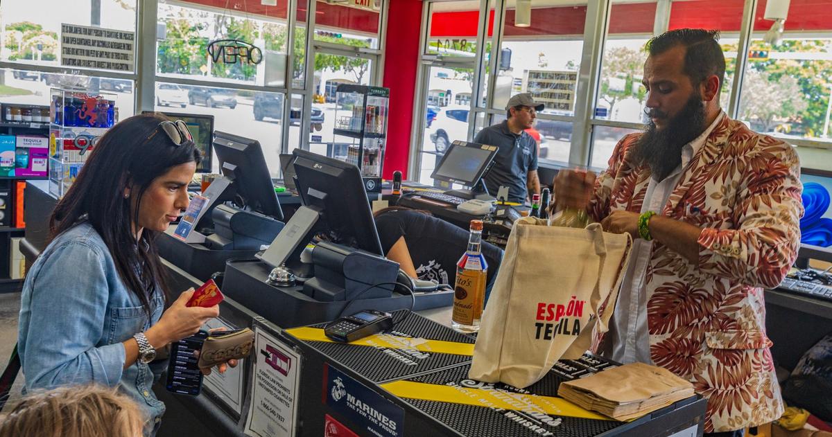 El gerente de la tienda Jensen's at Sunset Corners, Bruno Barbato, ayuda a la diseñadora de vestuario Jennifer Leven durante una cata de vinos el 1 de junio de 2024, en el emblemático negocio familiar.