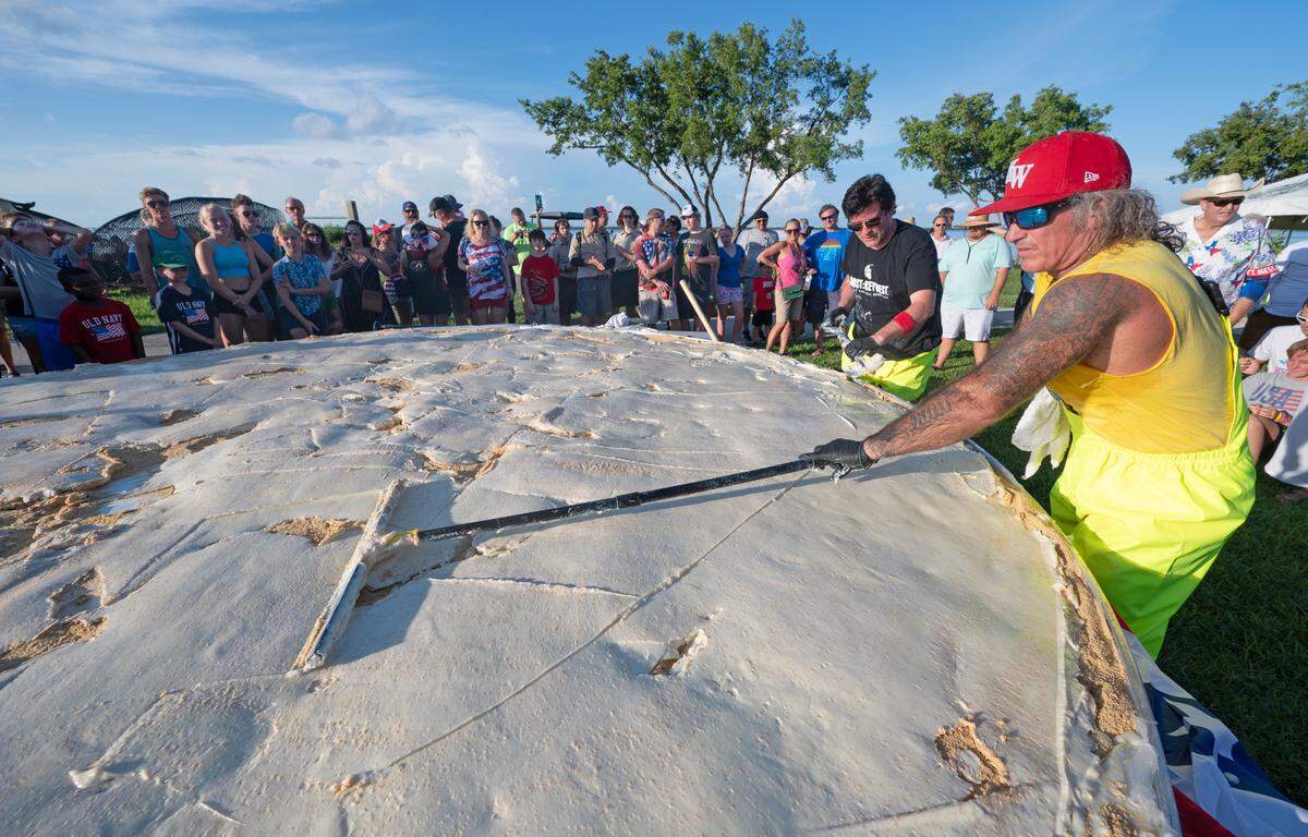 In this photo provided by the Florida Keys News Bureau, chefs Paul Menta, front right and David Sloan, back right, put finishing touches on a gargantuan Key lime pie created for a 200th Florida Keys birthday celebration Monday, July 3, 2023, on Big Pine Key, Fla. The festivities took place on the 200th anniversary of the Florida Territorial Legislature’s establishment of Monroe County, which contains the entire Keys island chain and a portion of Everglades National Park, on July 3, 1823. The pie measured 13.14 feet in diameter and contained 16 gallons of Key lime juice, and Keys officials intend to have it recognized as world’s largest. FOR EDITORIAL USE ONLY (Andy Newman/Florida Keys News Bureau/HO)