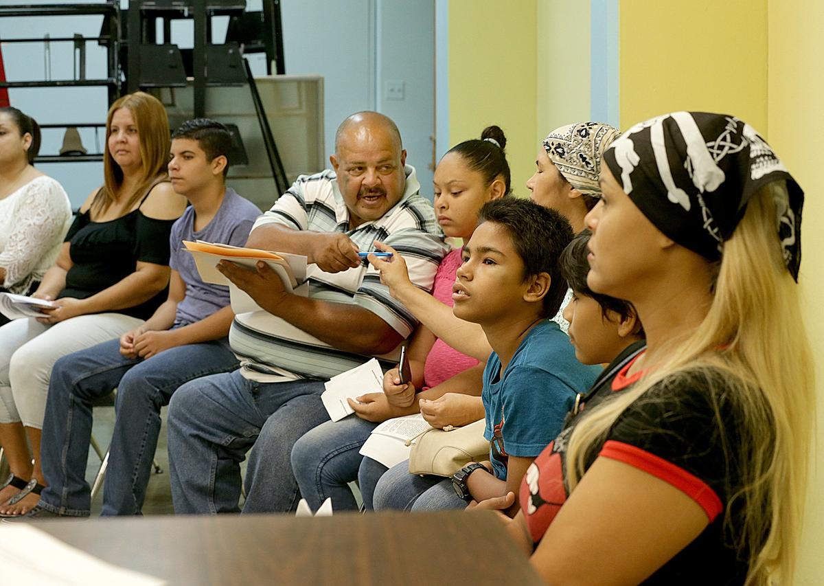Felipe Velázquez and his daughter Genesis Velázquez (fourth and fifth from left) attend a meeting at Rosa Costa Valdivieso Middle School, where Genesis was relocated after her school, Marcos Sánchez, was closed.