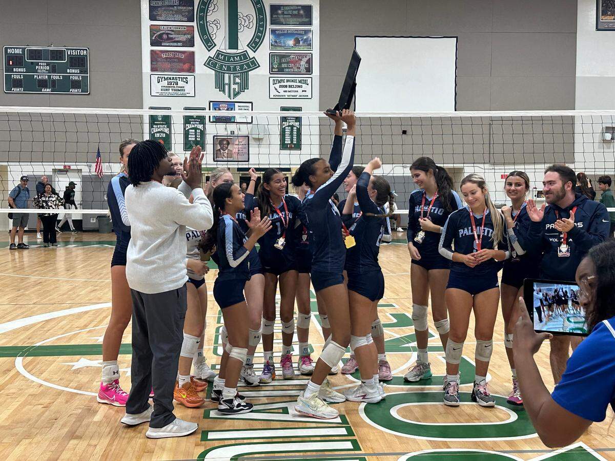Miami Palmetto volleyball players and coaches celebrate after being presented the GMAC championship trophy on Saturday night at Miami Central High School.
