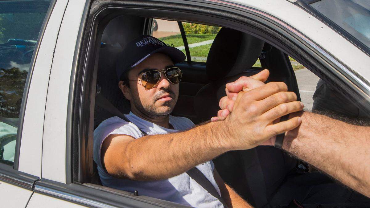 Christopher Monzón, el activista del Partido Republicano que fue atacado en Hialeah mientras repartía volantes para el senador Marco Rubio, saluda a sus partidarios durante un mitin de los Proud Boys en Hialeah al aparecer en público por primera vez luego de salir del hospital.