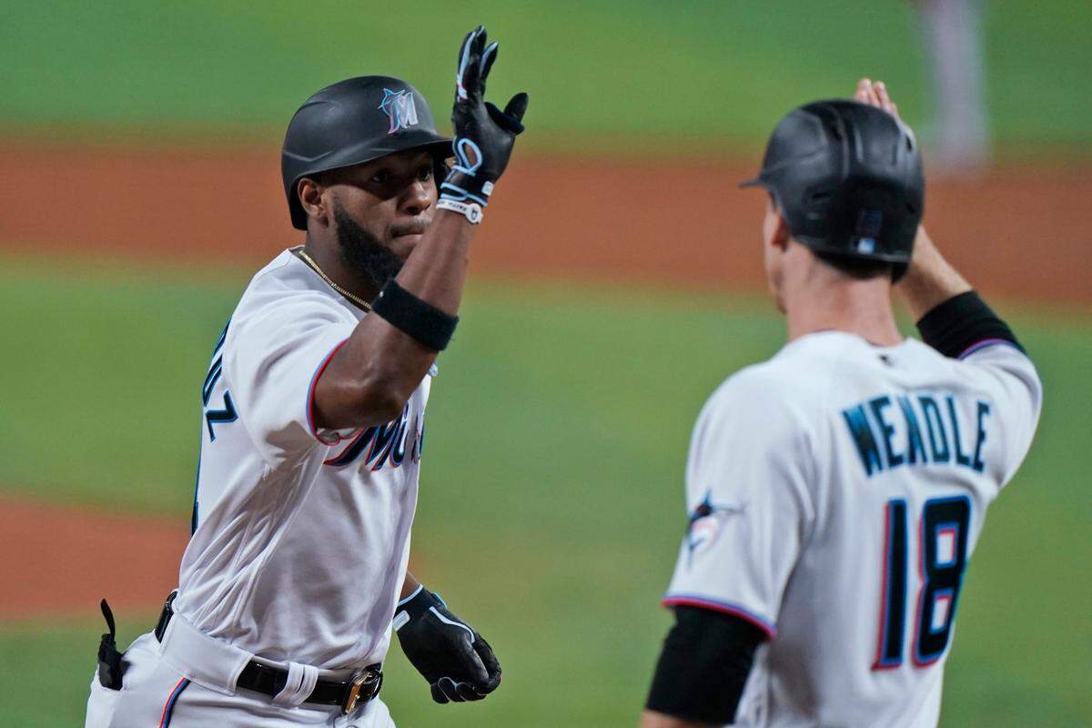 Miami Marlins’ Bryan De La Cruz, left, is congratulated by Joey Wendle (18) after De La Cruz hit a home run scoring Wendle during the third inning of a baseball game against the Atlanta Braves, Monday, Oct. 3, 2022, in Miami. (AP Photo/Wilfredo Lee)