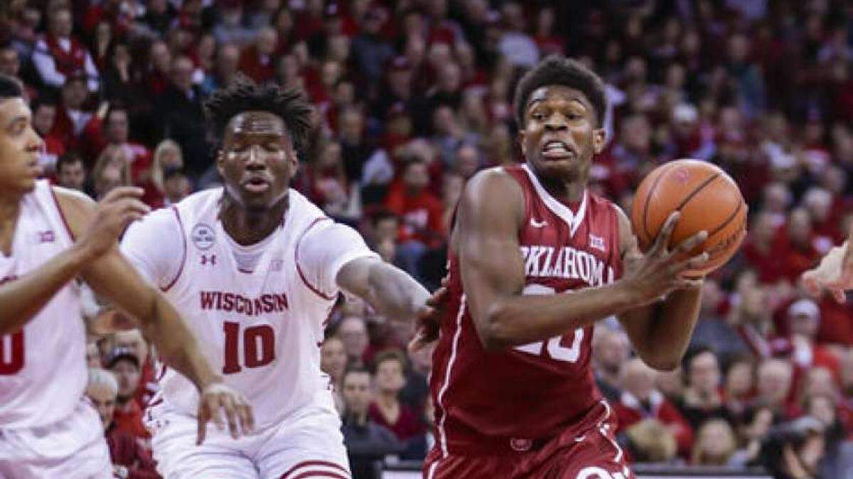 Oklahoma guard Kameron McGusty (No. 20) drives past a Wisconsin player during a game on Dec. 3, 2016. McGusty announced on Apr. 16, 2018 that he will transfer to the University of Miami.