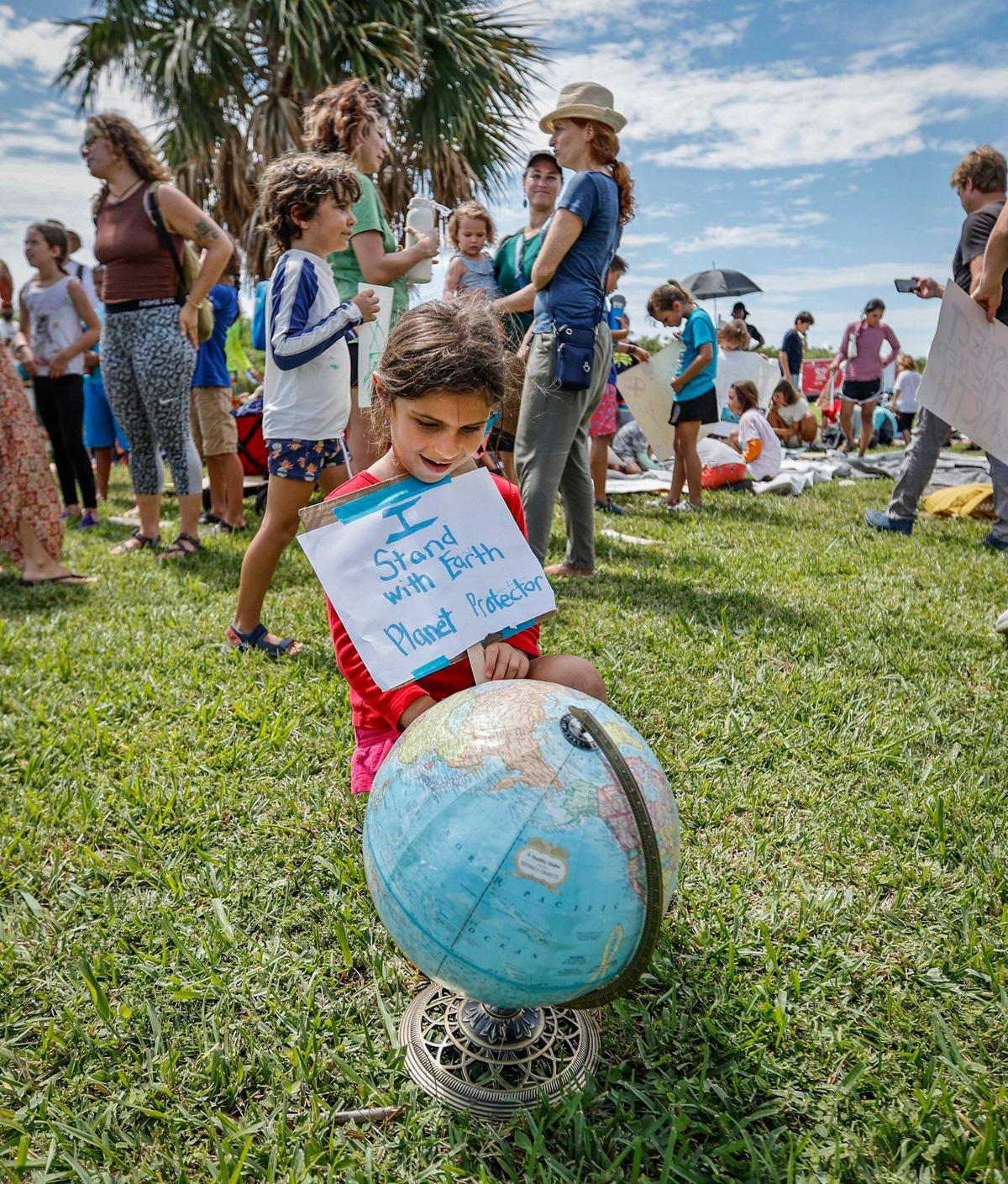 Adi Perl, 6, with Take Root Forest School, views a globe of the planet as she joins protesters with Keep Florida State Parks Wild-Defend Oleta State Park against the Florida Department of Environmental Protection’s plan to add pickleball courts, cabins, and a disc golf course to Oleta River State Park in North Miami Beach, Florida on Tuesday, August 27, 2024.
