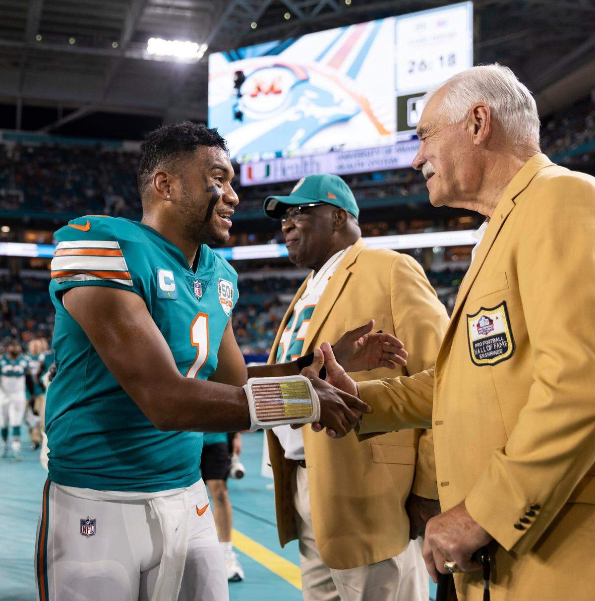 Miami Dolphins quarterback Tua Tagovailoa (1) shakes hands with former Miami Dolphins fullback Larry Csonka before the start of an NFL football game between the Dolphins and the Pittsburgh Steelers at Hard Rock Stadium on Sunday, Oct. 23, 2022, in Miami Gardens, Fla.