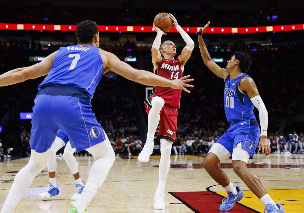 Miami Heat guard Tyler Herro (14) shoots the ball around Dallas Mavericks guard Max Christie (00) and forward Dwight Powell (7) during the first half of a game on Nov. 24, 2025, at Kaseya Center in Miami.