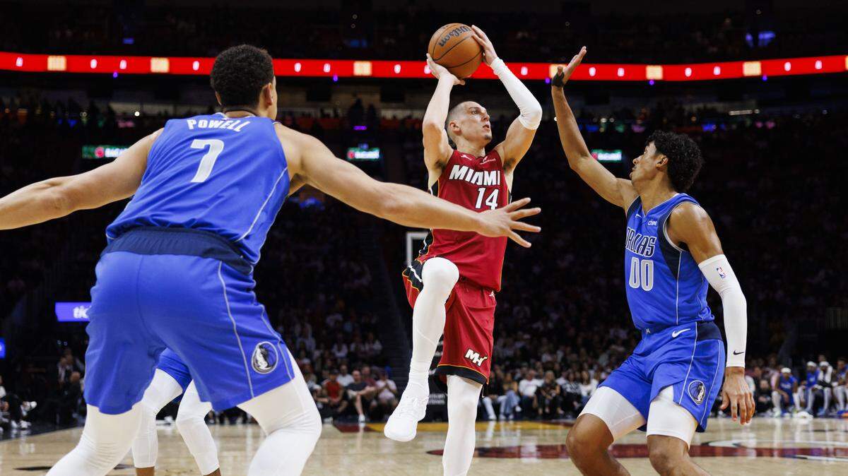 Miami Heat guard Tyler Herro (14) shoots the ball around Dallas Mavericks guard Max Christie (00) and forward Dwight Powell (7) during the first half of a game on Nov. 24, 2025, at Kaseya Center in Miami.