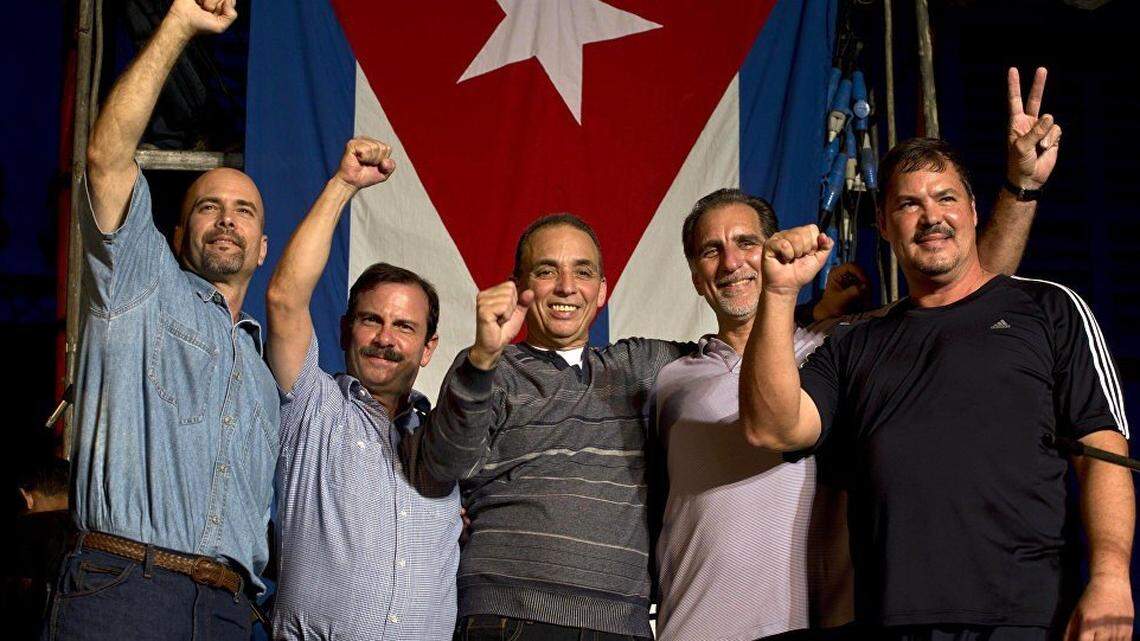The five Cuban spies pose for a photo in front of a flag in Havana.