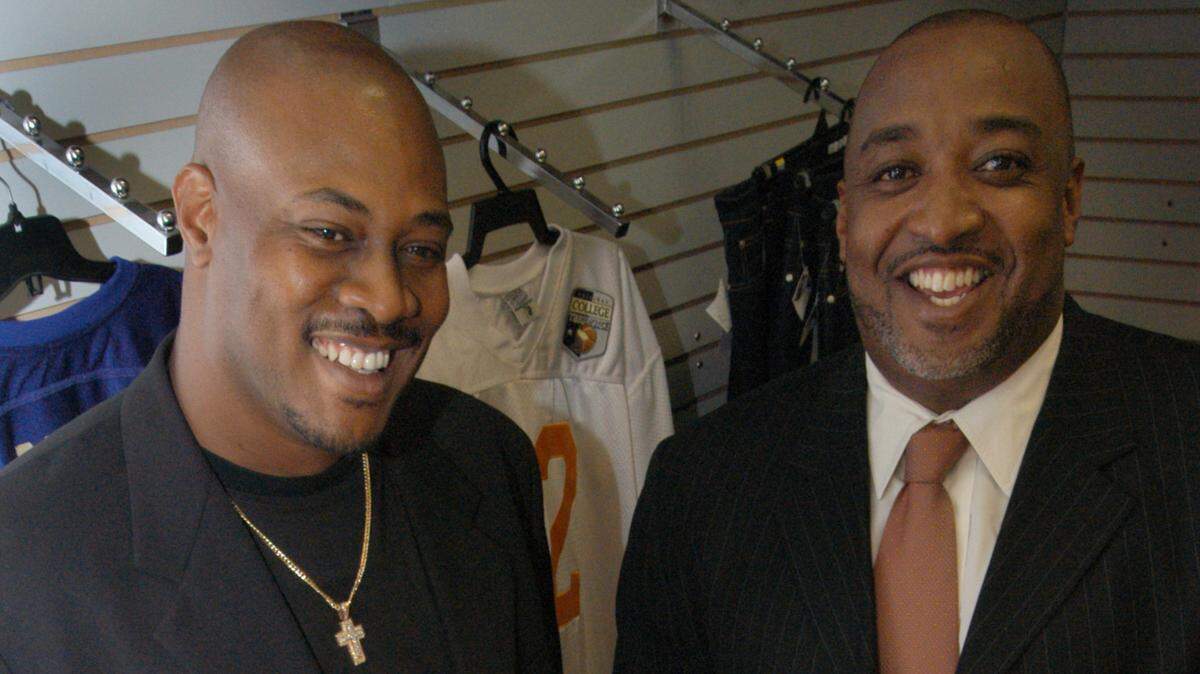 07/31/03 - Noelle Theard/Herald Staff Former football players Tolbert Bain, left, and Melvin Bratton, right, have started a college throwback jersey business in South Florida. Here they show their merchandise at Viagari Sportwear in Miami.