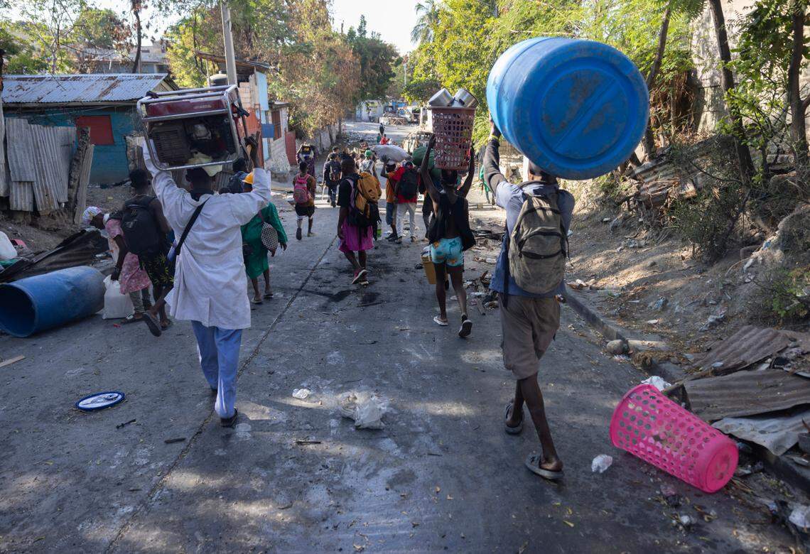 Gang members carry stolen goods after a raid in a neighborhood of Port-au-Prince on Dec. 7, 2024.