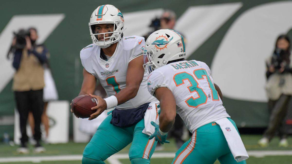 Miami Dolphins quarterback Tua Tagovailoa, left, hands off to Myles Gaskin during the second half of an NFL football game against the New York Jets, Sunday, Nov. 21, 2021, in East Rutherford, N.J. (AP Photo/Bill Kostroun)