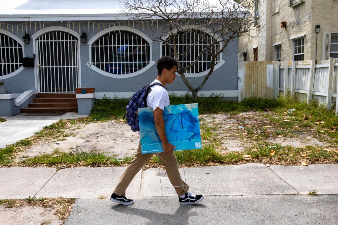 Bernardo, a freshman at Miami Senior High, walks home from school with his Underwater Marker in hand indicating his home’s elevation above sea level in Miami.