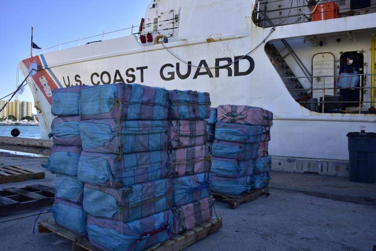 Bales of contraband are stacked in front of the Coast Guard Cutter Dauntless at Base Miami Beach, Dec. 7, 2021. The contraband was part of more than $148 million of illegal narcotics offloaded by the Dauntless crew.