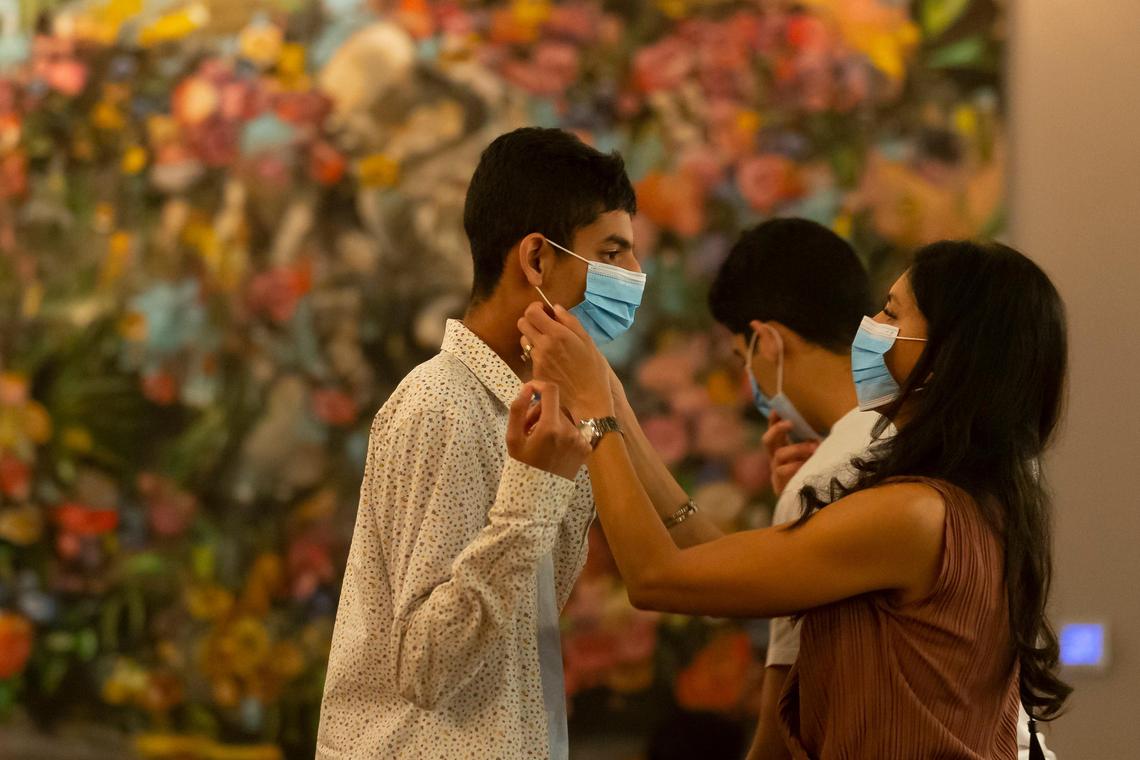 Manisha Patel, right, helps her son put on a face mask after she and family had dinner at Ghee Indian Kitchen. Diners must wear masks when they move about the restaurant and may take them off after they sit down.