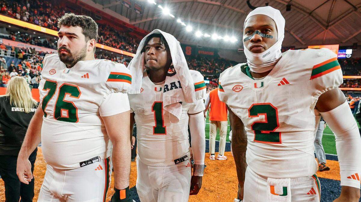 Miami Hurricanes offensive lineman Ryan Rodriguez (76) quarterback Cam Ward (1) and wide receiver Isaiah Horton (2) walk off the field after the Syracuse defeat the Canes 38-42 in their NCAA football game in the JMA Wireless Dome at Syracuse University, Syracuse, New York on Saturday, November 30, 2024.