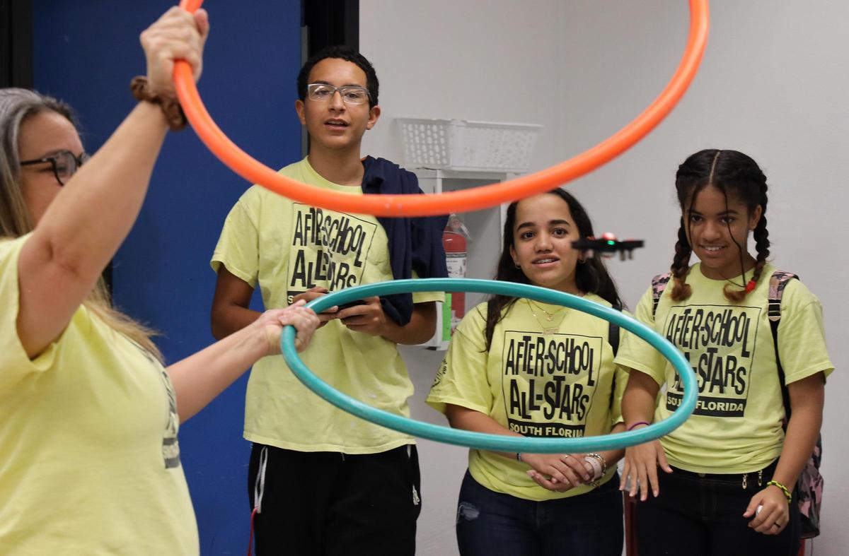Teacher Aida G. Talavera, left, holds hula hoops as Brandon Gutierre, 14, navigates a small drone through the two hoops and Alexandra DeJesus, 11, and Nicole Vera, 11, right, look on on Wednesday, July 24, 2019 at Ruben Dario Middle School. Florida Power & Light Company (FPL) partnered with After-School All-Stars South Florida to start the Discover Drones program, teaching low-income middle school students a world of innovation and technology.
