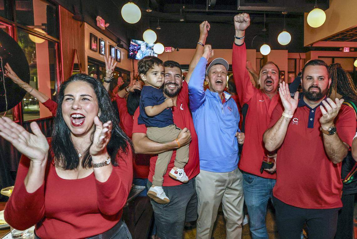 Christopher Columbus High School alumnus, friends and family react during a watch party at Vice Pizza in South Miami, FL., as Indiana Hoosiers quarterback Fernando Mendoza wins the Heisman Trophy on Saturday, December 13, 2025. Celebrating, left to right are, Lourdes Rayneri, Avian Guerra holding his son Julian Guerrra, 2, Tom Kruczek, Rudy Puig and Nick Ramos.