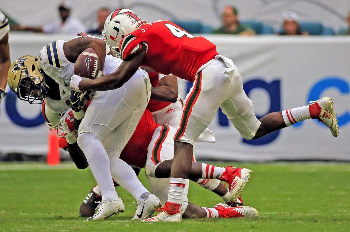 Miami Hurricanes defensive back Jaquan Johnson (4) rips the ball away from Pittsburgh Panthers running back Darrin Hall (22) who fumbles in the first quarter as the Miami Hurricanes hosts the Pittsburg Panthers at Hard Rock Stadium in Miami Gardens on Saturday, November 24, 2018.