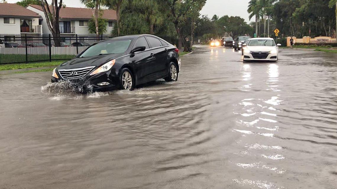 A car hits a submerged pothole while driving through flooded streets near Hialeah on November 10, 2020.