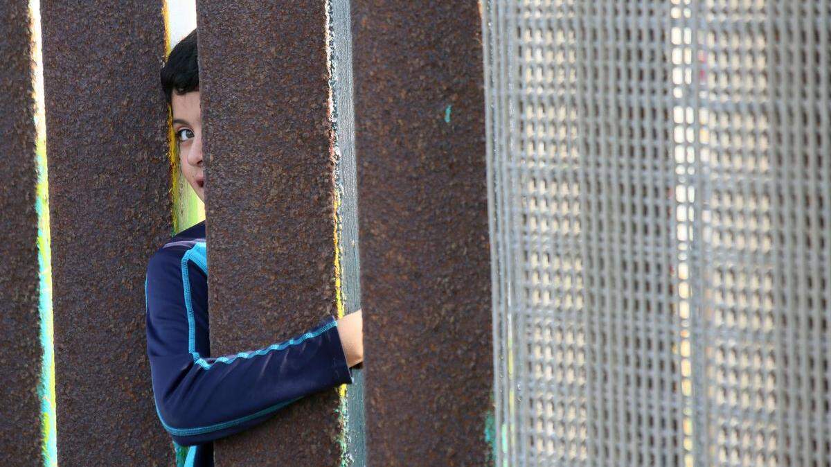A Mexican boy reaches his arm through the border fence in San Ysidro, California in 2016.