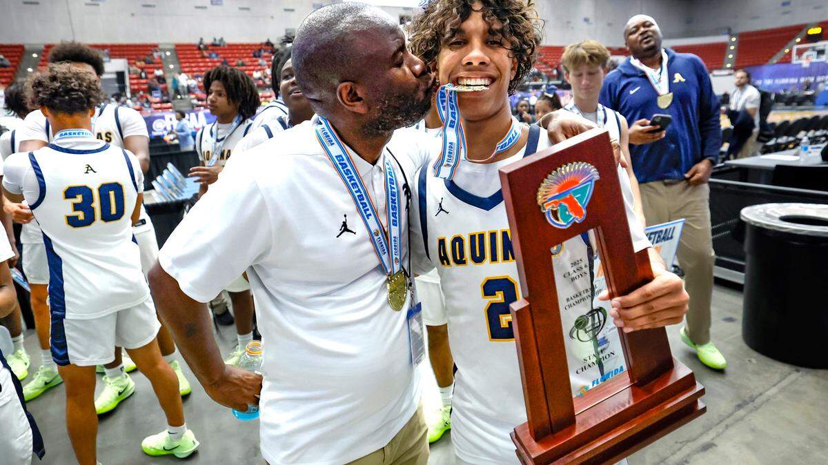 St. Thomas Aquinas Raiders head coach Julius Sandi kisses his son DJ Sandi (2) as they celebrate the win over Evans for the FHSAA Class 6A Boys High School Basketball State Championship.