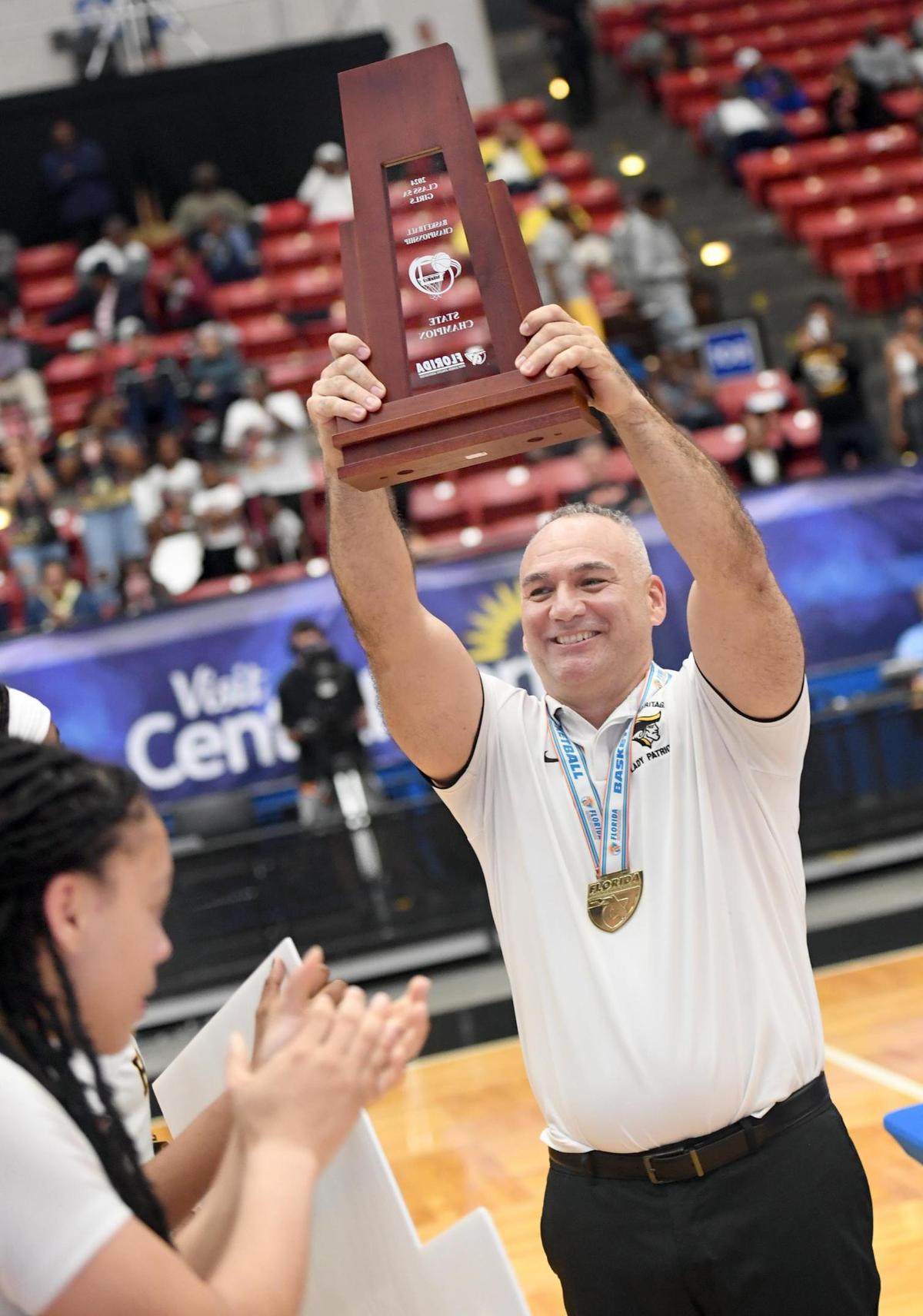American Heritage head coach Greg Farias hoists the trophy after his team defeated Mainland in the Class 5A final during the Florida High School State Championships at the RP Funding Center in Lakeland, Fl on Friday March 8, 2024. American Heritage defeated Mainland 60-55 to win the Class 5A State Title. Scott Wheeler | Photo