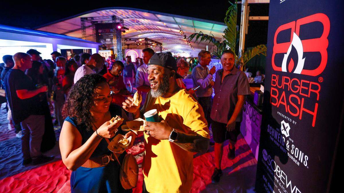 Dana and Efren Johnson try out burgers during the 2023 Burger Bash at the South Beach Wine & Food Festival on the beach by the Ritz-Carlton Miami Beach.