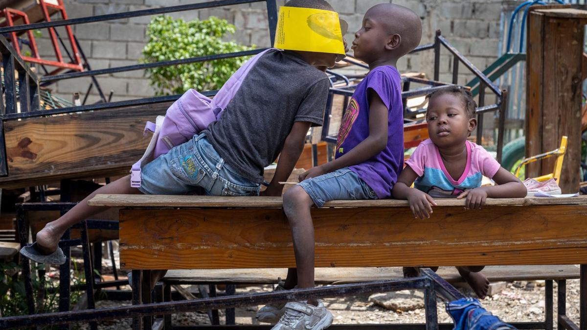 Children play on school desks that have been taken out of classrooms so people can sleep inside at Ecole National Joseph C. Bernard DeFreres displacement camp on August 27, 2024. Residents of areas in Port-au-Prince have been forced to take refuge in camps such as this rather than stay in gang occupied territories.
