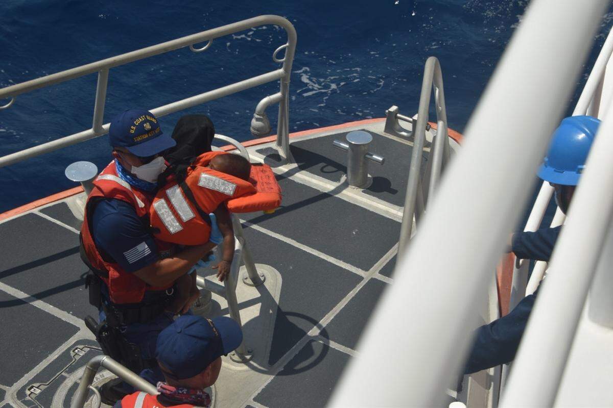 A Coast Guard crewmember carries a baby that was part of a group of interdicted Haitian migrants on April 24, 2021, about 10 miles east of Lake Worth, Florida. The Coast Guard Cutter Charles Sexton’s crew repatriated 72 Haitian migrants to Haiti on April 27, 2021.